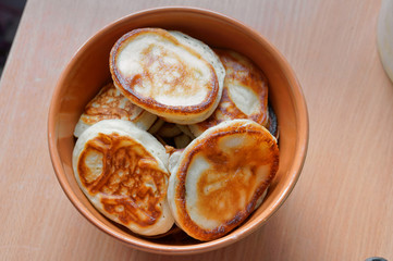 Pancakes in a deep bowl. Fragrant pancakes in a plate. Round small pancakes in a deep plate.