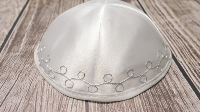 Jewish traditional white kippah on a table with the camera turning around