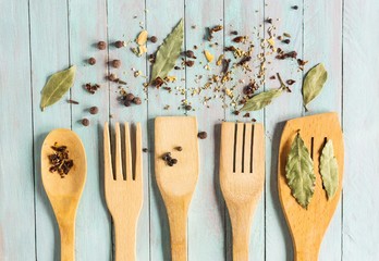wooden kitchen utensils and various spices on an old table