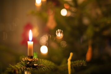 Burning candle on Christmas tree with decoration in elegant festive mood