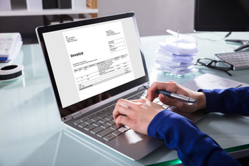 Obraz na płótnie Canvas Businessperson Analyzing Invoice On Laptop