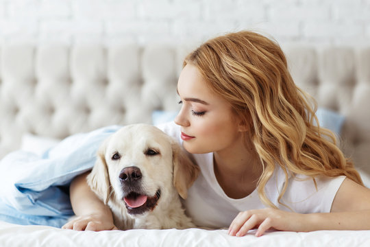 Beautiful teen girl with golden retriever dog in a bed