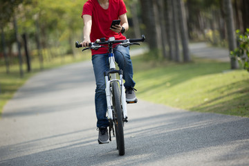 cyclist use cellphone while riding bike in tropical park