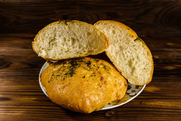 Plate with italian bun ciabatta on wooden table