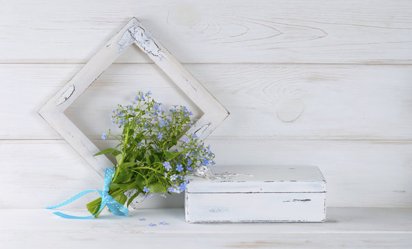 Forget-me-not flowers bouquet, vintage casket and photo frame on white wooden shabby board