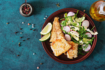 Fried white fish fillet and cucumber and radish salad. Top view