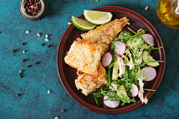 Fried white fish fillet and cucumber and radish salad. Top view