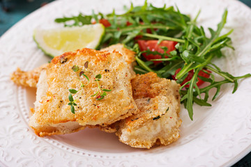 Fried white fish fillets and tomato salad with arugula.