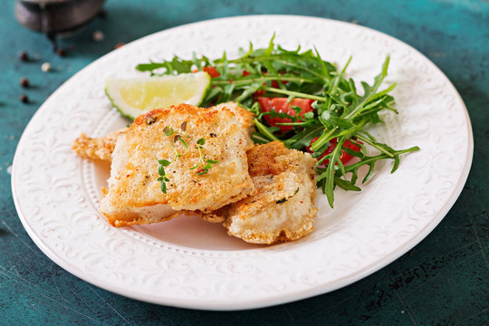 Fried white fish fillets and tomato salad with arugula.