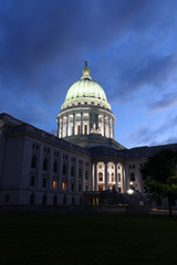 Wisconsin state capitol building at dusk. Night scene with illuminated entrance and glowing at the dark dome against dark blue sky. City of Madison, Wisconsin, Midwest USA. Vertical composition.