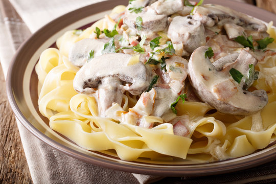Traditional Italian fettuccine with Boscaiola sauce, mushrooms, bacon close-up on a plate. horizontal