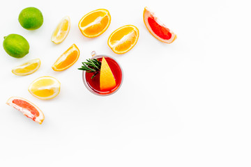 Concept of alcoholic cocktail with fruits. Glass with beverage near oranges, grapefruit, lime and rosemary on white background top view copy space