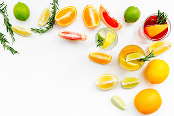 Concept of alcoholic cocktail with fruits. Glass with beverage near oranges, grapefruit, lime and rosemary on white background top view copy space