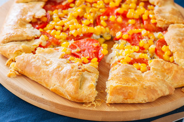 Close up of tomato and sweet corn galette on a wooden board.