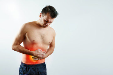 Naklejka premium Front view, the man holds his hands to the stomach, abdominal pain, pain in the stomach highlighted in red. Light background. The concept of medicine, massage, physiotherapy, health.