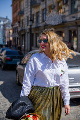 A woman of plus size, American or European appearance walks in the city enjoying life. A young lady with excess weight, stylishly dressed in jacket at the center of the city. Natural beauty 