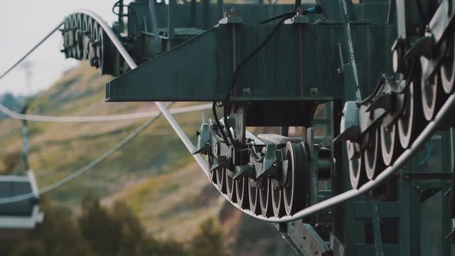 Funitel lift cabin riding over green trees in rocky mountains, hight pole metal wheels contraption
