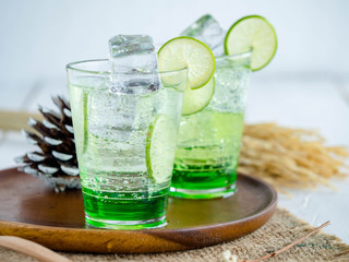 Green Lemon soda in glass on wood tray and white table