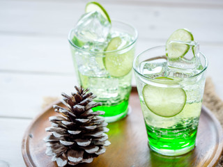 Green Lemon soda in glass on wood tray and white table