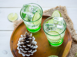 Green Lemon soda in glass on wood tray and white table
