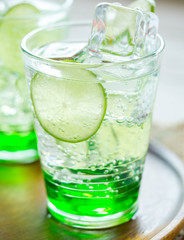 Green Lemon soda in glass on wood tray and white table