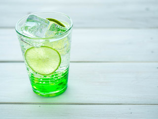 Green Lemon soda in glass on wood tray and white table