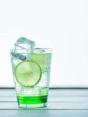 Green Lemon soda in glass on wood tray and white table