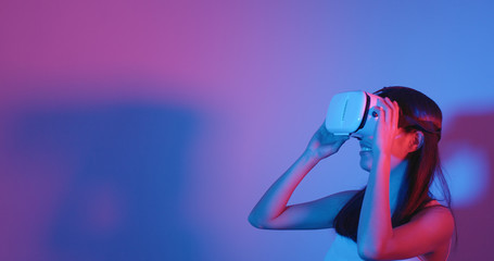 Woman watching with VR device with cyber lighting