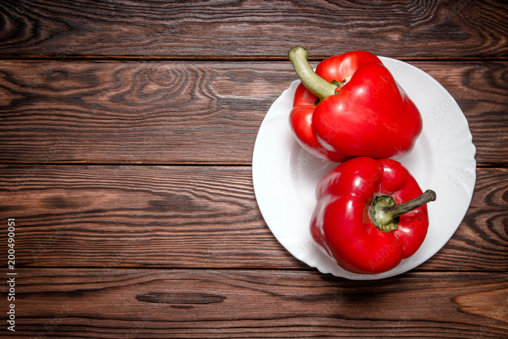 Wall mural Two red peppers lying on a brown background 