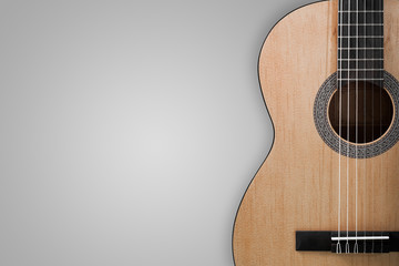 Part of an acoustic guitar on a grey background.