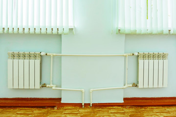 Two radiators of heating under the windows are connected by plastic pipes with power controllers