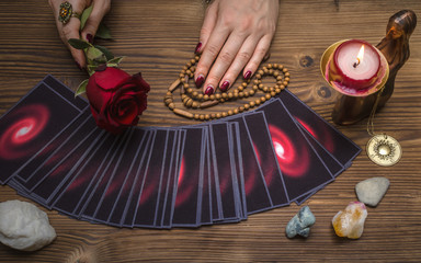 Tarot cards and future reading concept. Fortune teller holding in hands a red rose flower and...