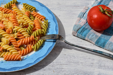 Delicious homemade colorful pasta whit meat sauce and fresh tomato at white wooden background