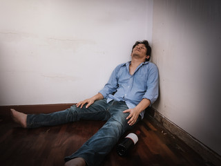 A man drunk sitting against a sleeping while, he was disappointed in life.