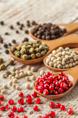Different pepper in a wooden spoons on wooden table