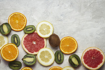 Fresh Tropical Fruits, Grapefruit, Lemon, Orange, Kiwi on a Light Stone Background. Copy space and a top view