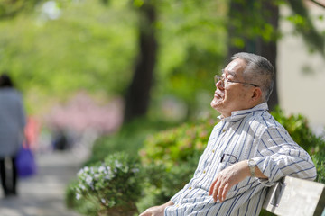 公園のベンチに座っているシニア男性