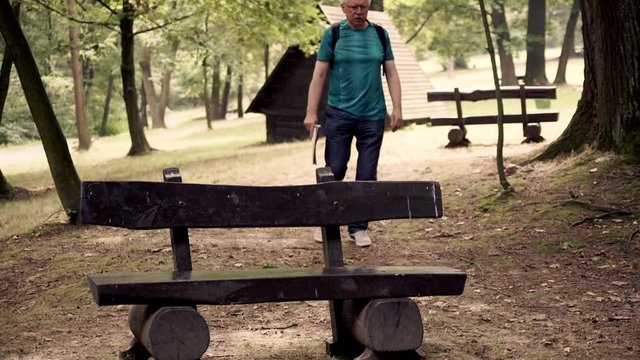 Senior man having problem with leg after hiking in forest
