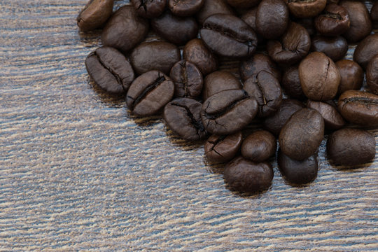 Coffee beans on a dark background and a wooden table. Closeup.