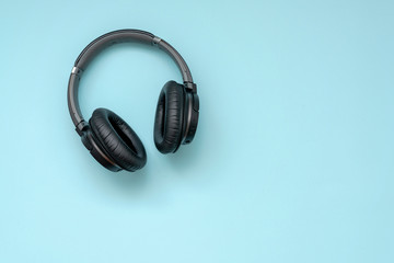 Fototapeta na wymiar Modern black wireless headphones on a blue background. The concept of music and fashion.