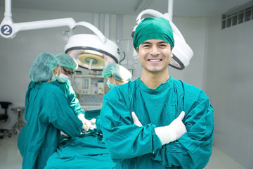 Fototapeta na wymiar Young male doctor looking to camera with attractive smile at operating room background. Medical concept.