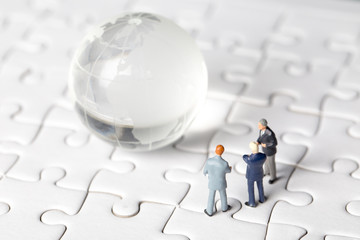 Miniature of investor man looking to  world and jigsaw background. Business man control world. Business and Investment concept.
