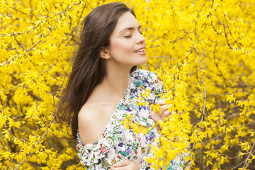 Young woman in the flowered, yellow garden in the spring time