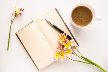 Colorful spring flowers, with blank open diary for text and cup of coffee, on white background.