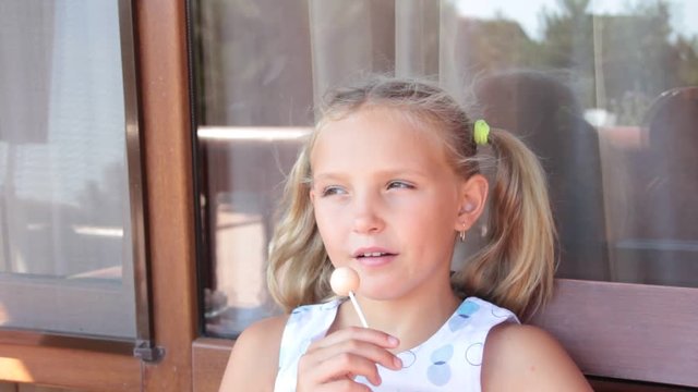 little girl eating candy on the street