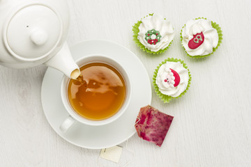 pouring tea on white table with christmas cupcake