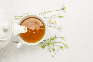 pouring herbal tea into cup on white table - obrazy, fototapety, plakaty