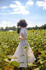 Girl  in the sunflowers field holding old vintage camera taking photo enoying the sun picking up flower dancing laughing spinning and talking with big smile / red lip stick