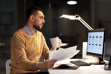 Fototapeta premium business, software development, deadline and technology concept - man with papers, coffee and user interface mockup on computer screen working at night office