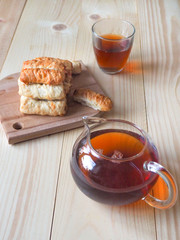 Tea with biscuit puff rolls on a wooden table.
